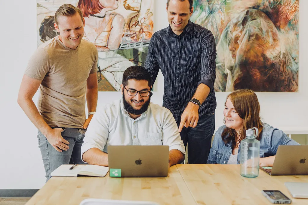 Colleagues gathered around a laptop, relaxed and smiling